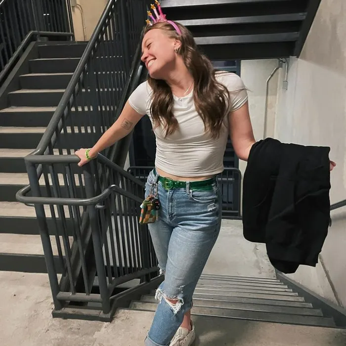Allie Bennett happy coming up the staircase wearing a party headband