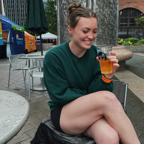 Allie Bennett drinking and laughing at outdoor cafe | Female influencers