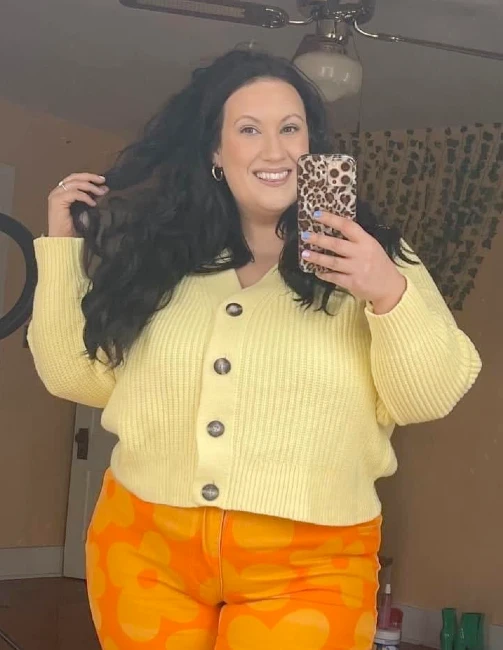 Chelsea Metzger in a yellow cardigan taking selfie with leopard print case
