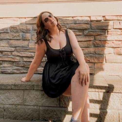 Emily Abercromby sitting on a brick wall | Body Positivity Influencers Featured on Afluencer
