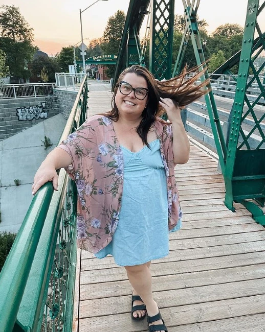 Emily Inson in blue dresses posing on a river bridge