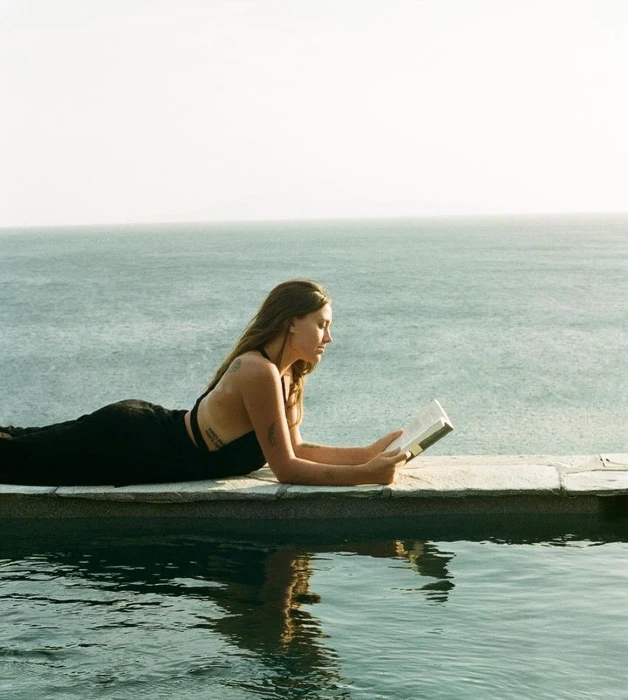 Emma Marschall lying on her front on a jetty reading a book