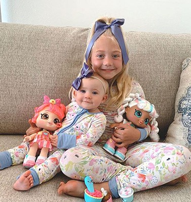 Kid Influencer with baby and dolls on sofa