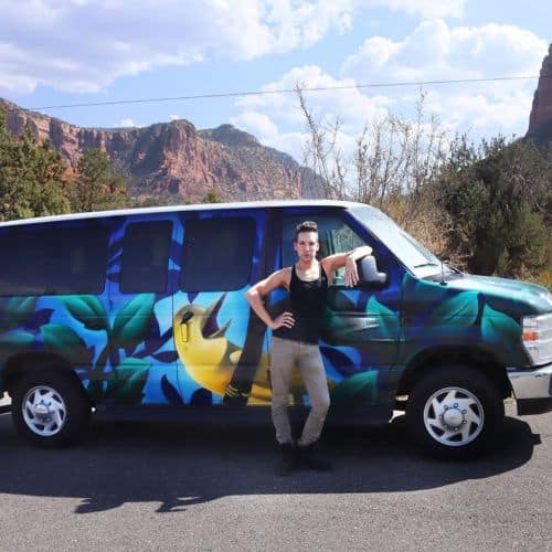 Justin Honard aka Alaska from RuPaul's Drag Race posing with his van