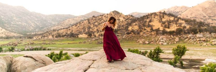 Myla Ivers in red dress posing in the mountains