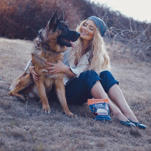 Olya Hill in a field with a dog and pack of treats